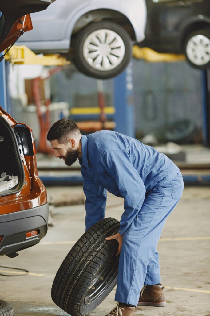 Man replaces wheel in car in garage on rise