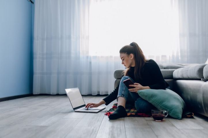 a girl sitting on a floor and using her laptop